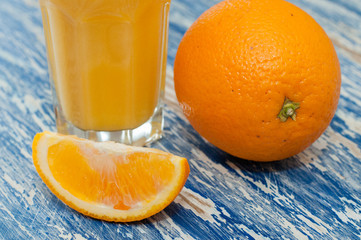 Glass of orange juice, whole orange and orange slice on sea blue background