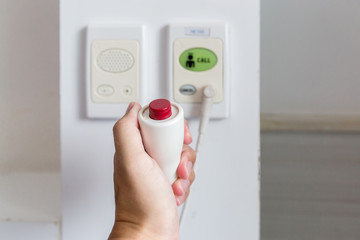 hand pushing nurse call button . patient press red emergency button to calling nurse for help in hospital. Mother hand pressing emergency nurse call button while her daughter have a high fever.