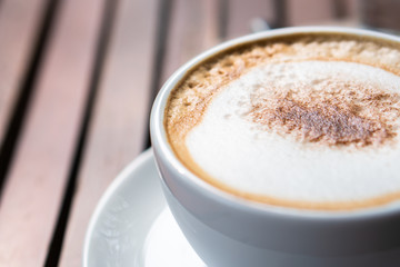 Hot coffee placed on the wooden table in early morning with copyspace, white cup and silver spoon. The green background with defocus effect.