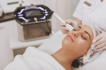 Young beautiful woman visiting osmetologist, getting skin treatment. Cropped shot of a professional...