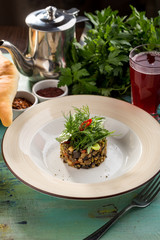 Baked eggplant with pepper on top and glass of berry drink on blue wooden table