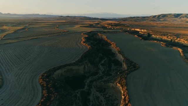 Aerial drone shot of agriculture fields and plantations in middle of dry desert during dusk or dawn. Beautiful moode colors of untouched nature. Farming and irrigation canals