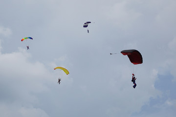  Four skydivers is flying in the blue sky against the background of clouds.