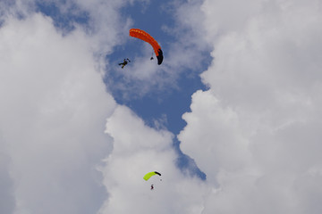  Skydivers is flying in the blue sky against the background of clouds. Tandem parachutists in the sky on a sunny day