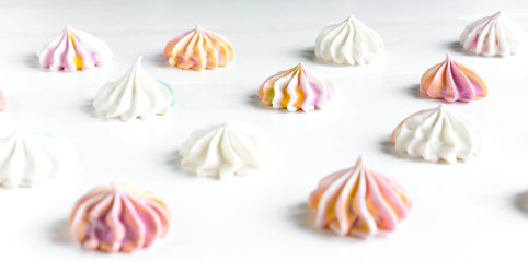 Multi-colored meringue on a white background. Sweets on the photo. Pattern with meringue on a white background. Sweet holidays