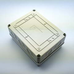 Obraz premium Plastic gray plastic electrical installation junction box on a white background. Electric switchboard on the white wall of a factory.