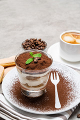 Classic tiramisu dessert in a glass and cup of coffee on concrete background