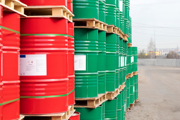 Barrels of 200 liters of metal are in the pallet on the street. Red and green barrels for petroleum, chemicals, gasoline. Close-up.