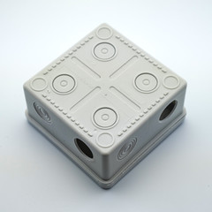 Obraz premium Plastic gray plastic electrical installation junction box on a white background. Electric switchboard on the white wall of a factory.