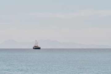 a ship on the sea in the middle of the day with mountains in the background