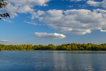 Obraz premium sunny summer day by the lake with blue water and white clouds in the sky