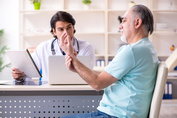 Fototapeta premium Old man visiting young male doctor 