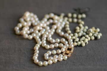 White rosary and pearl necklace on linen fabric. Luxury and modesty.