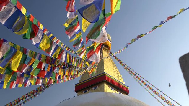 Colorful flags with Buddhist scriptures inscribed on them hanging tied to the Boudhanath stupa in Kathmandu, Nepal. The Stupa is said to entomb the remains of Kasyapa Buddha. 4K