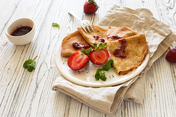 Pancakes with fresh strawberries and jam close up