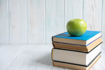 Photo of a stack of books with an apple and a place for an inscription on a wooden background. Accounting, school, study, students. Concept on the topic of study