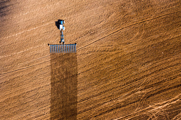 Spring agricultural work in the fields. Plowing and harrowing the soil with a tractor. The view...