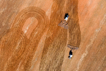 Spring agricultural work in the fields. Plowing and harrowing of the soil with tractors. The view...