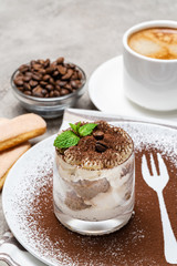 Classic tiramisu dessert in a glass and cup of coffee on concrete background
