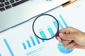 Obraz premium Businessmen use a magnifying glass to analyze the company's data and statistics from the chart.