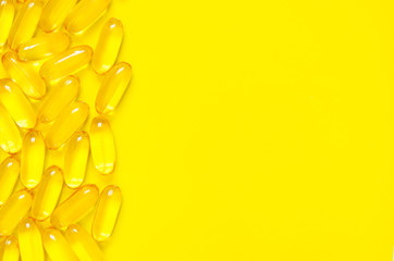Omega 3 fish oil capsules on yellow background. Concept of healthcare. Top view, flat lay, copy space.