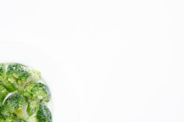 Frozen broccoli on a white plate. Top view, flat lay, copy space.