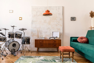 Stylish compositon of retro home interior with vintage cupboard, velvet sofa, black marble  drums setup, lamps , elegant accessories and abstract paintings. Minimalistic concept. Nice home decor. 