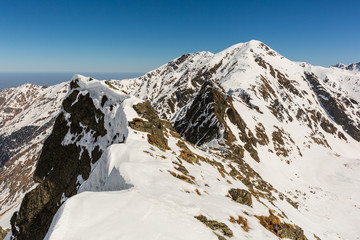 Fototapeta na wymiar winter landscape with the mountain peaks covered by heavy snow. aerial view by drone. romanian mountains, Negoiu peak, Fagaras Mountains