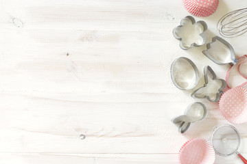 Set of cookies cutters and paper tins on a white wooden background