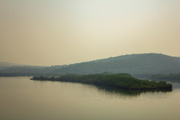 small island with green trees against the backdrop of a misty river valley