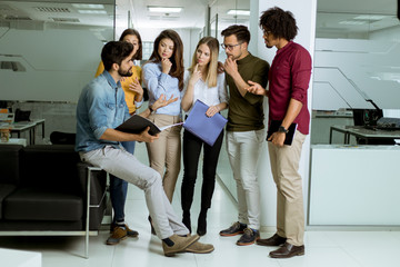 Multiethnic group of young people standing in the modern office and brainstorming