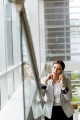 Young business woman stands on the stairs at the office and use mobile phone