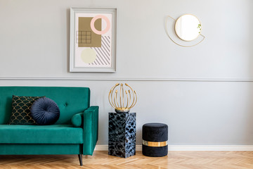 Stylish and luxury living room of apartment interior with elegant green sofa, retro lamp, marble stands, design pouf, chic accessories and gold mirror. Mock up frames on the molding gray wall. Home.