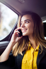 Fototapeta na wymiar Young businesswoman talking on mobile phone in car