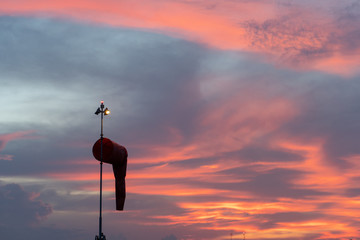 Wind sock under at the dawn under the red orange glowing sky with cirrus and cumulus clouds