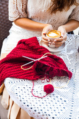 Young Woman knitting on terrace in Cafe