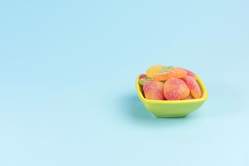 Small bowl with gummy candies isolated on blue background.