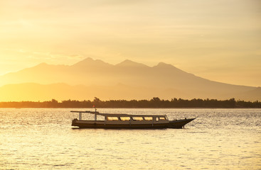Boat on seashore during the sunrise. Sky and reflections on the water in the summer. Sun rays during the sunrise. Gili Meno, Indonesia. Travel - image