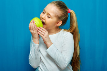 Little girl biting green apple.