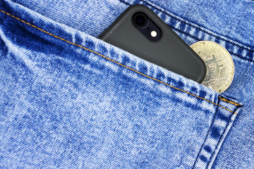 Bitcoins emerging from app on handheld smartphone to illustrate mobile money or the use of a cellphone to make online payments securely using blockchain technology or fintech