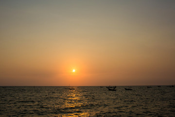 Bright sunset with large yellow sun under the sea surface. sunrise in the sea. Beautiful sunset above the sea. Tropical sunset on the beach.