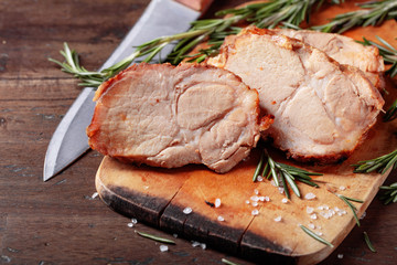 Oven-baked pork with rosemary and spices on a wooden table.