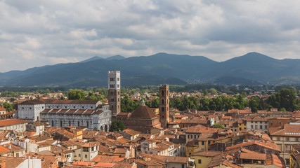 St Martin Cathedral and towers over houses, against mountain landscape, in Lucca, Tuscany, Italy