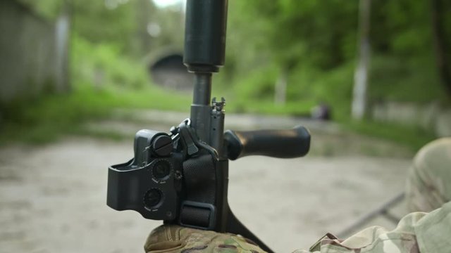 A fully equipped soldier winds up a silencer with a rifle. Special operation.