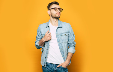 Elegant, fashion and stylish photo of handsome confident man in jeans and glasses. Guy is posing in studio 