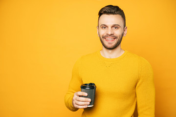 Smiling young student man with cup of coffee looks on camera