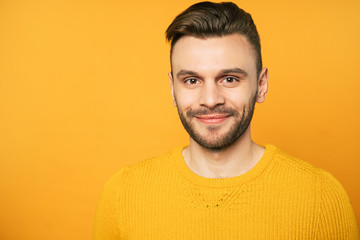 Obraz premium Close up portrait of happy handsome man in yellow is posing over orange background