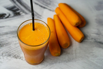 Fresh carrot juice in a glass on a dark white background
