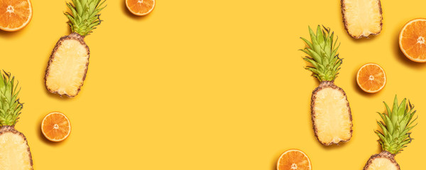 Fototapeta na wymiar Juicy tropical fruits on a yellow background: oranges, coconuts, lemons, pineapples.