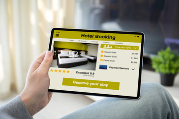 man hands holding computer tablet with app hotel booking